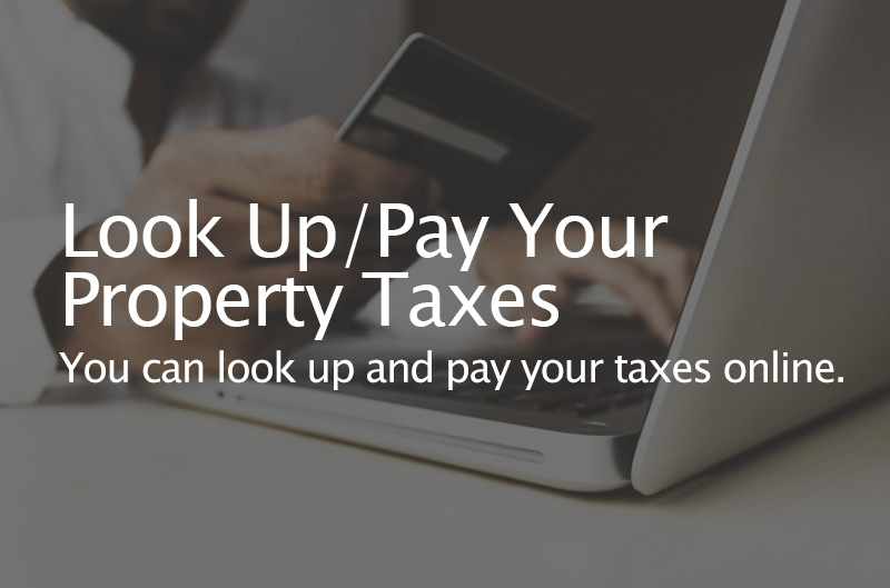 Photo backdrop of person paying online with credit card. Caption: Look Up / Pay Your Property Taxes. You can look up and pay your taxes omloine or use our My Property app.
